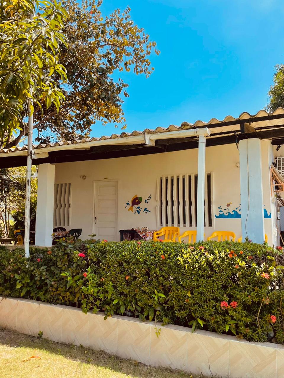 Fachada de Villa Sofía Cabañas con su terraza, sillas amarillas y jardín florido bajo el cielo del Caribe